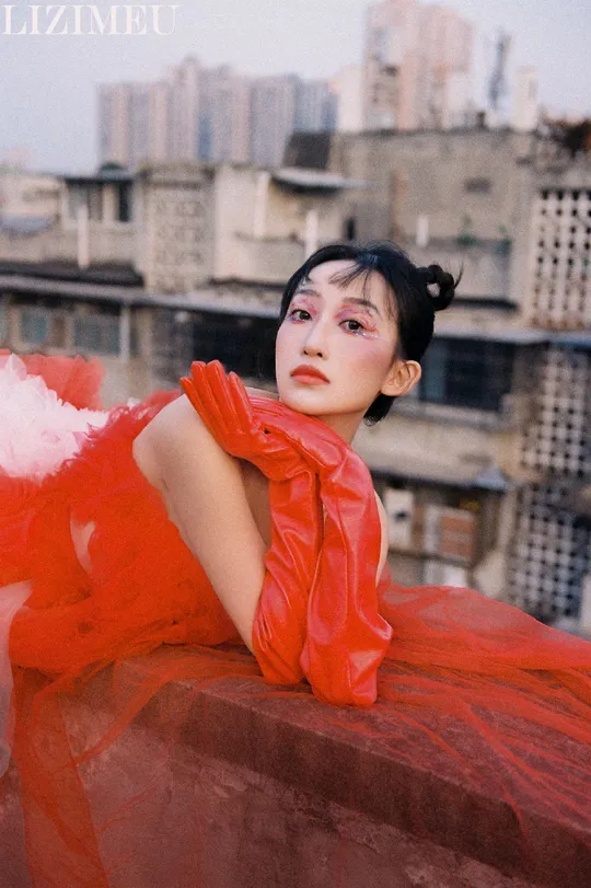 一位穿红裙子的模特站在屋顶上