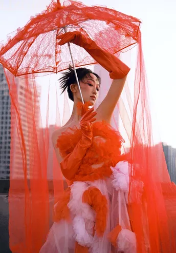 一位穿着橙色连衣裙 拿着红色雨伞的女人
