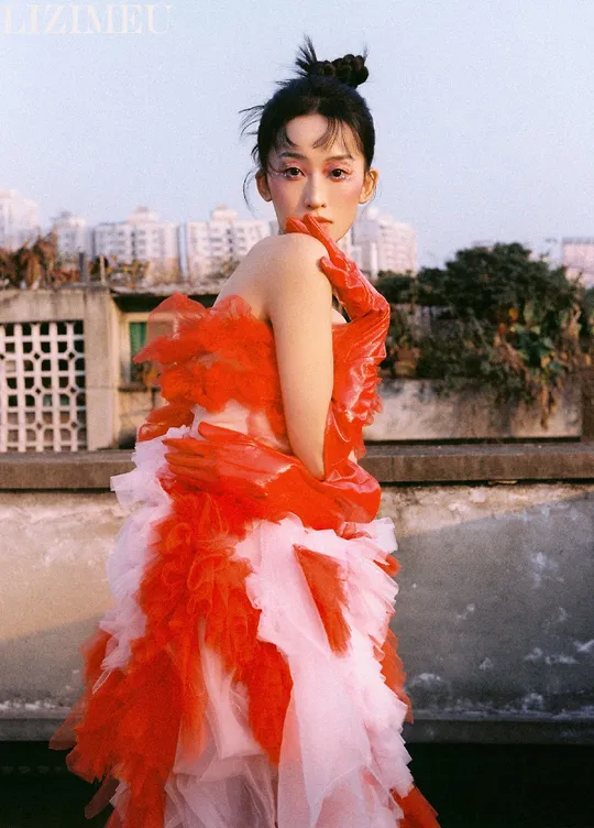 一位穿着红白相间 gown 的模特儿站在屋顶上