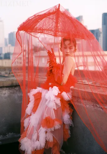 一位穿着红色连衣裙的女人坐在遮阳伞下