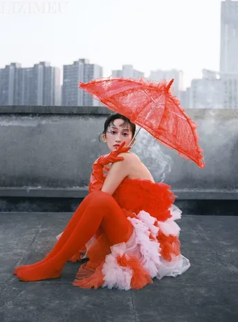 一个穿橙色连衣裙的女孩 带着一把红色的雨伞 站在屋顶上。