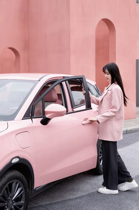 一位穿粉色衣服的女人正在从一辆粉色汽车中出来。