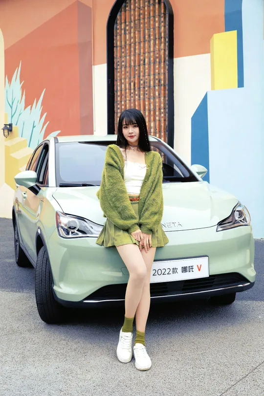 一位坐在绿色汽车前的女人
