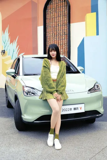 一位坐在绿色汽车前的女人