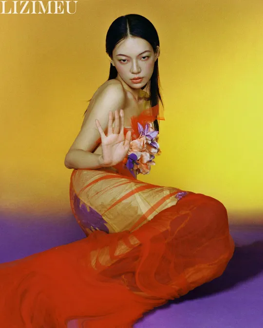 一位穿着橙红色连衣裙 胸前有花的女人
