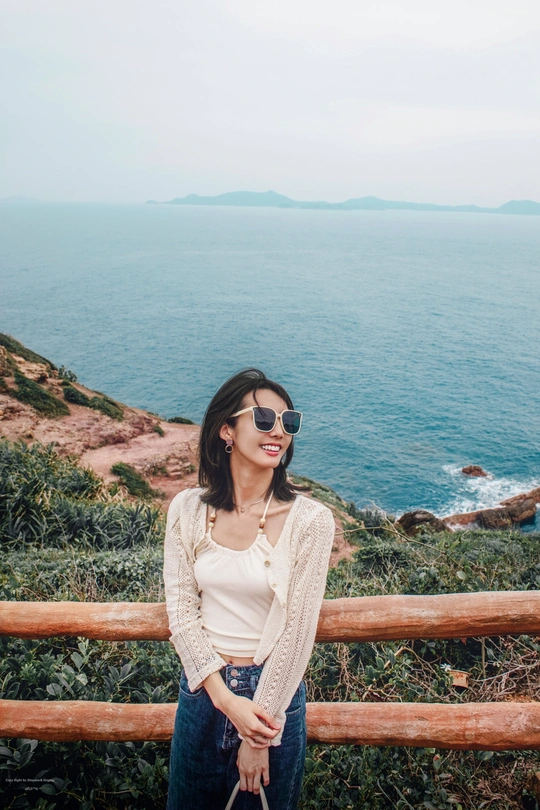 一个戴太阳镜的女人站在悬崖上 俯瞰海洋。