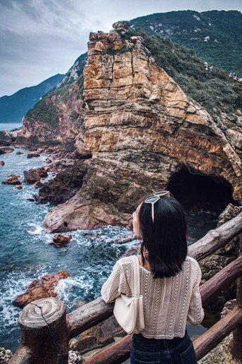 站在悬崖上的女人正在凝视着海洋和海滩