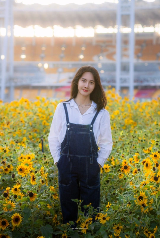 一位穿着工作服的年轻女子在黄花的田野中摆姿势