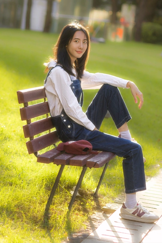 一位年轻女子坐在公园里的木凳上
