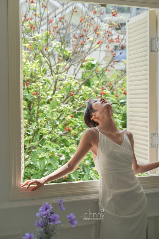 一个穿着白色连衣裙的女人从窗户向外看