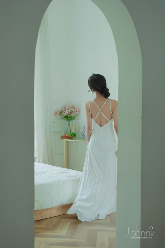 一个穿着白色连衣裙的女人站在窗前