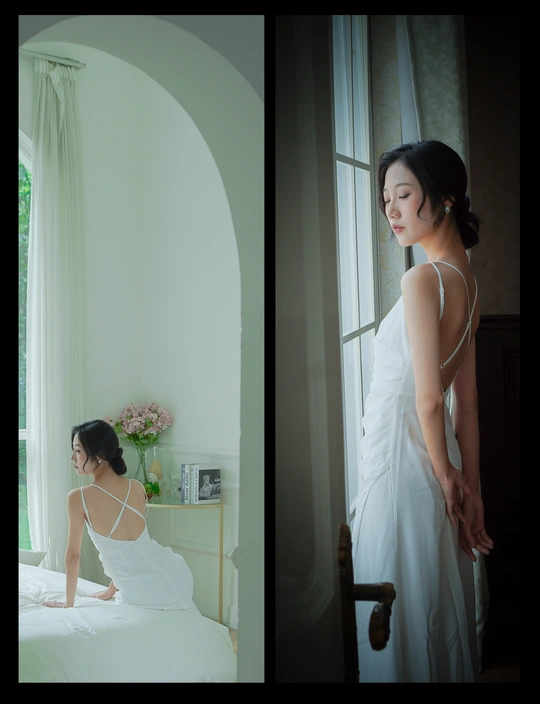 一个穿着白色连衣裙的女人站在床边看着窗外