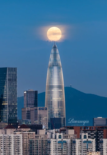 夜晚 满月升起在城市上 前景是一座高楼大厦。