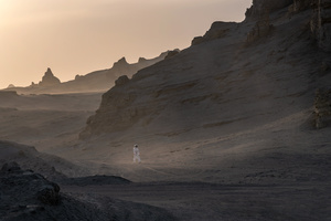 日落时 一名男子穿过沙漠 背景是山脉 前景是一个人