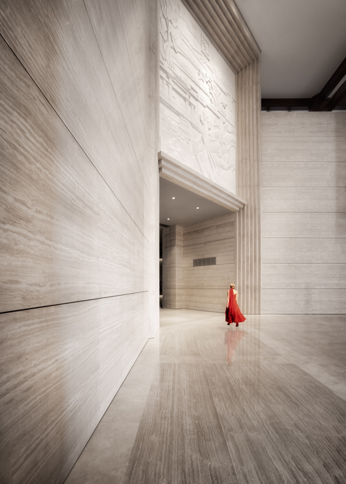 一个人穿着红色裙子在一座大型建筑物的白色大理石墙壁的走廊里走下来