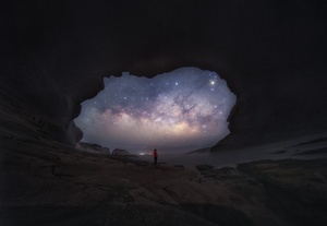 一个男子站在洞穴里仰望夜空中的星星