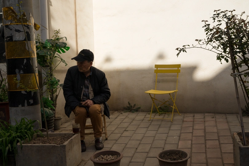 一个坐在有盆栽和黄色椅子的房间里的男人