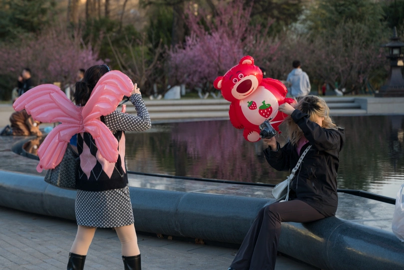 一位女士正在给穿粉色服装的女孩拍照