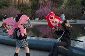 一位女士正在给穿粉色服装的女孩拍照