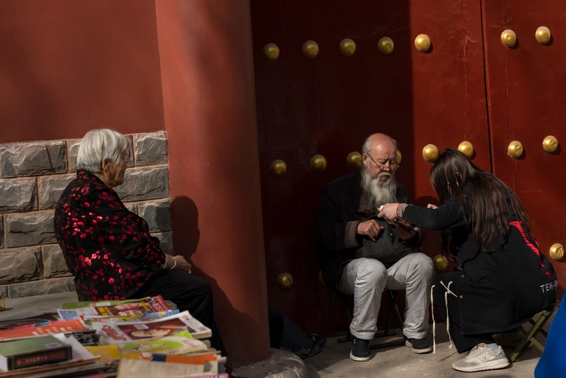 一个男子和一个女子坐在一个堆满书的房间里 面前是一扇红色的门。