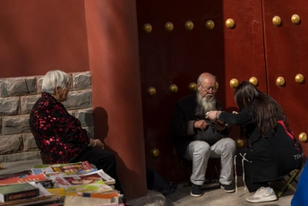 一个男子和一个女子坐在一个堆满书的房间里 面前是一扇红色的门。