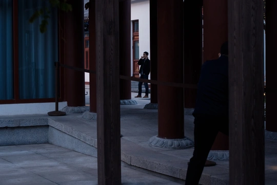 一个人站在一栋建筑旁边的人行道上