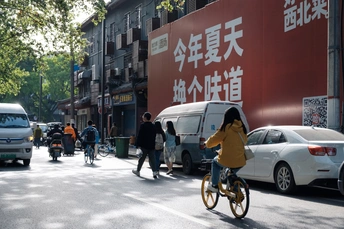 一个骑自行车的人在繁忙的街道上行驶 街道两侧有汽车和行人。