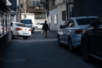 一条狭窄的巷子 两边停满了车 人们沿着街道走