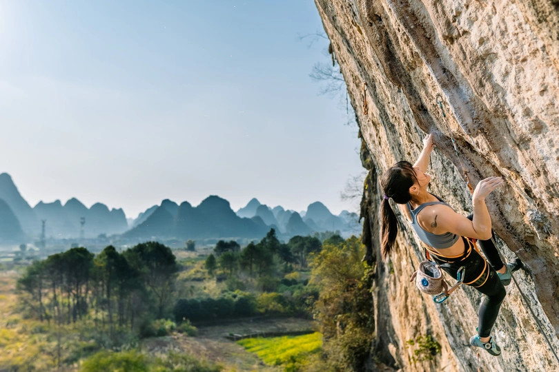 一位女攀岩者攀爬一座陡峭的山崖