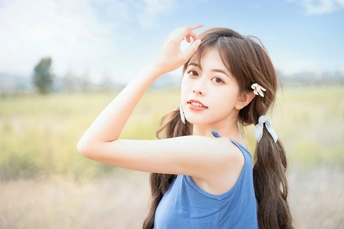 一位长发年轻女子穿着蓝色连衣裙站在田野中的人物肖像