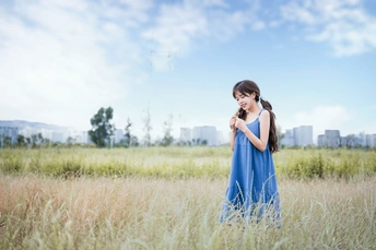 一个小女孩穿着蓝色裙子站在一片高草地上