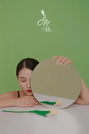 一位年轻女子拿着一朵白花看着镜子里的倒影