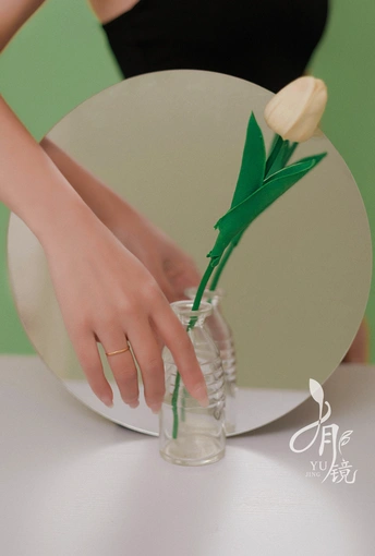 一位女士手持一束白色郁金香 放在一个装满水的透明花瓶中。