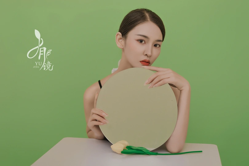 一位涂着绿色口红的年轻女子举着镜子照着她的脸