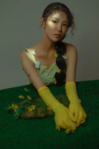 一位穿着绿色连衣裙和黄色手套 手里拿着花的女青年
