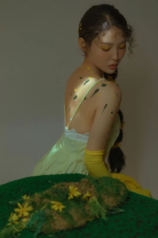 一位穿着绿色连衣裙的年轻女子坐在一个带有黄色花的绿色蛋糕前面。