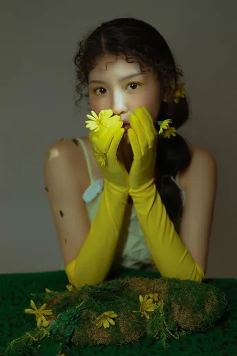 一个年轻女子坐在地上 手上戴着黄手套