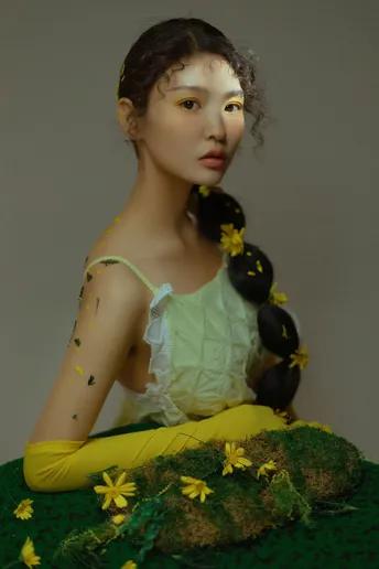一个穿着绿色连衣裙的年轻女子坐在一个绿色蛋糕上 蛋糕上有黄色的花朵。