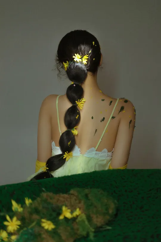一位穿着绿色连衣裙 头发上带有黄色花朵的年轻女子