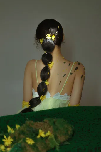 一位穿着绿色连衣裙 头发上带有黄色花朵的年轻女子