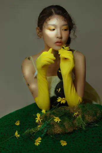 一位穿着黄色连衣裙 裙子上绿草和鲜花的女性