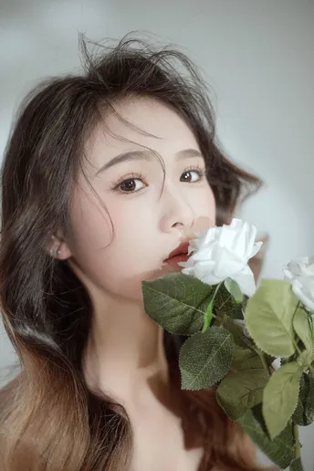 一位年轻女子嗅着白色花朵的肖像