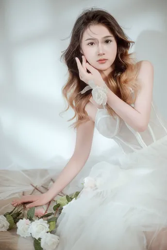 一位穿着白色连衣裙的美丽年轻女子坐在地板上 背景是新娘的肖像 白色背景照片