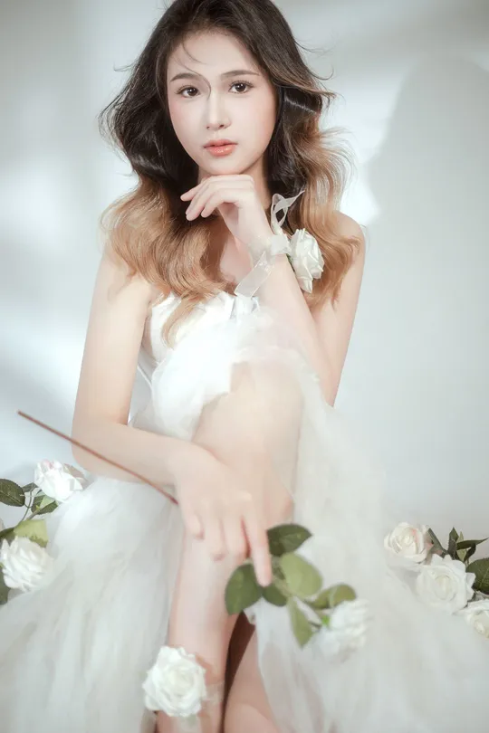 演员拍摄的一张美丽的女人穿着白色连衣裙 背景是白色花朵的照片