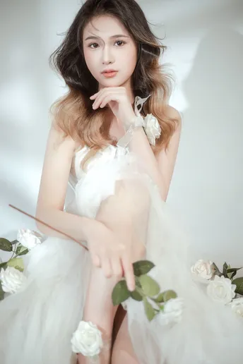 演员拍摄的一张美丽的女人穿着白色连衣裙 背景是白色花朵的照片