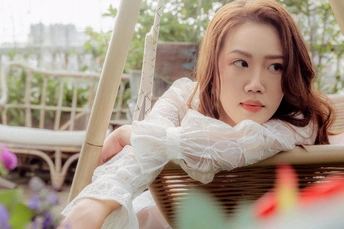 一个年轻女子穿着白色衬衫坐在秋千上 带着一篮花 一个年轻女子穿着白色裙子坐在桌子旁。