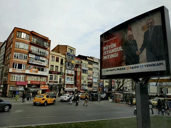 繁忙的城市街道 有许多汽车、出租车和行人 路边有一块大型广告牌。