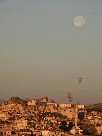 天空中的满月升起 热气球在村庄和建筑物上方飞行。