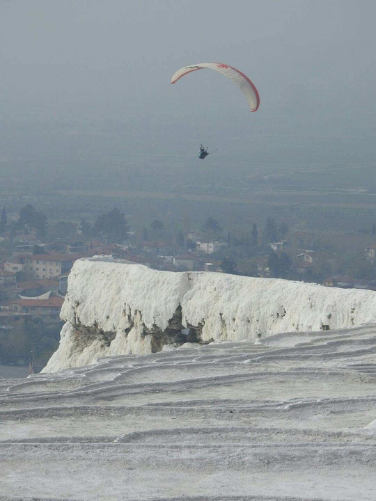 一个在雪山上放风筝的男子 背景中有直升机。