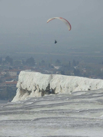 一个在雪山上放风筝的男子 背景中有直升机。